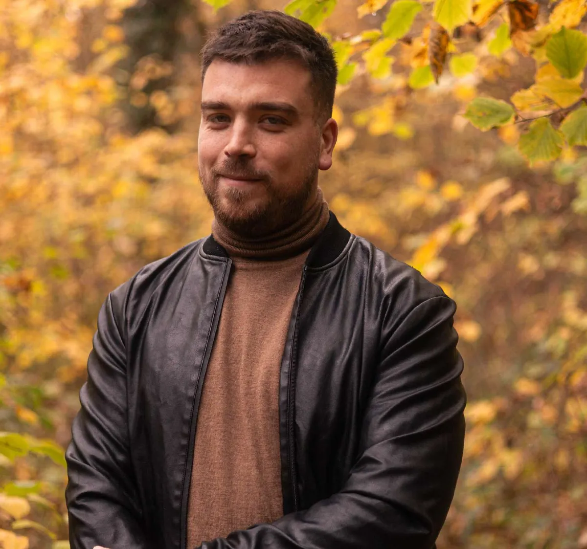 Portrait d’un homme en veste de cuir parmi les feuillages d’automne